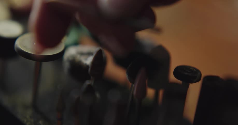 Fingers pick up and replace craft tacks in a black foam holder