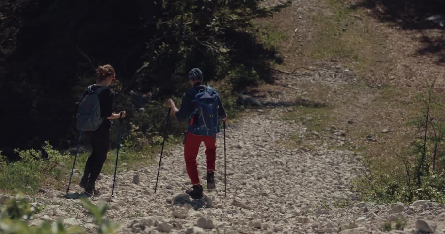 Young couple hiking down a gravel road in the mountains