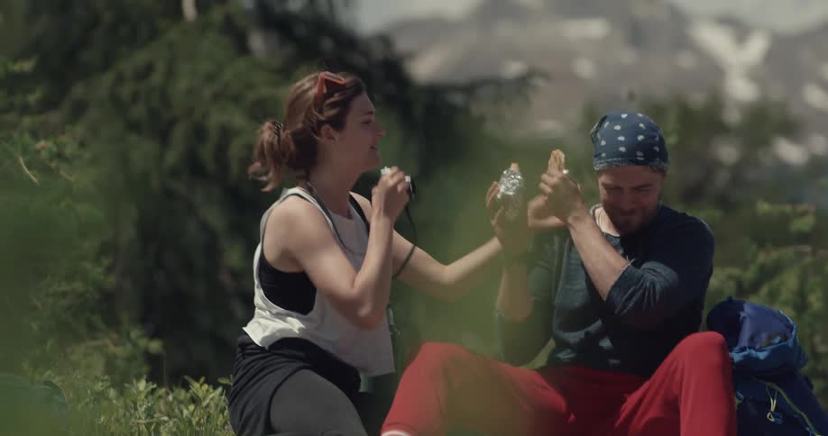 Young couple hiking in the mountains take pictures of themselves while eating