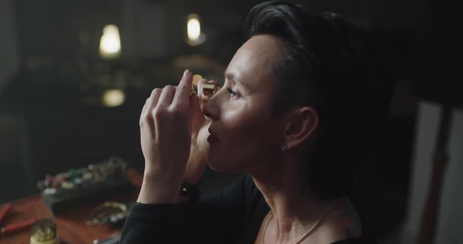 A woman looking at a ring with a loupe
