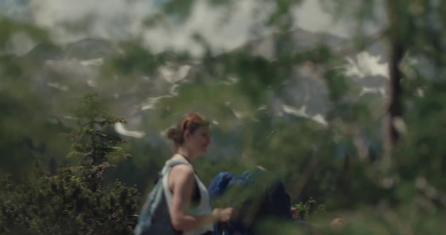 A man and woman use hiking sticks as they walk down a mountain trail