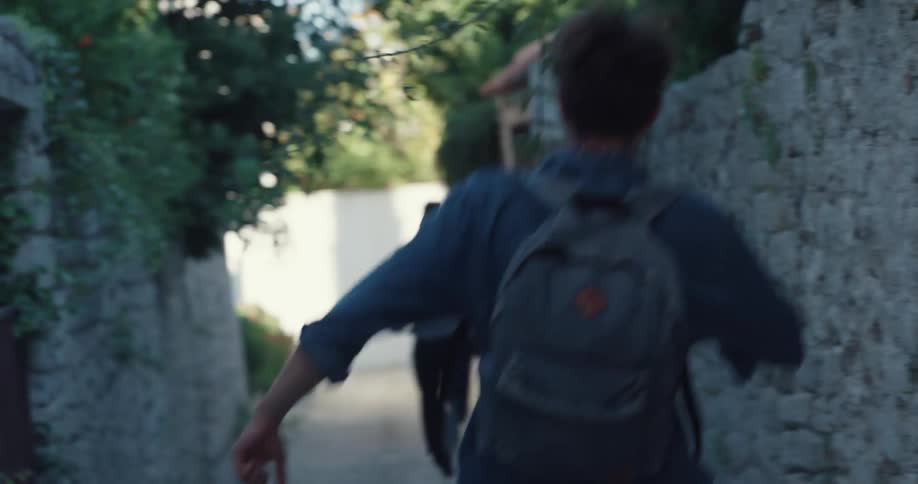 A couple stand near a stone wall looking at a phone screen when a thief runs by and grabs the womans purse