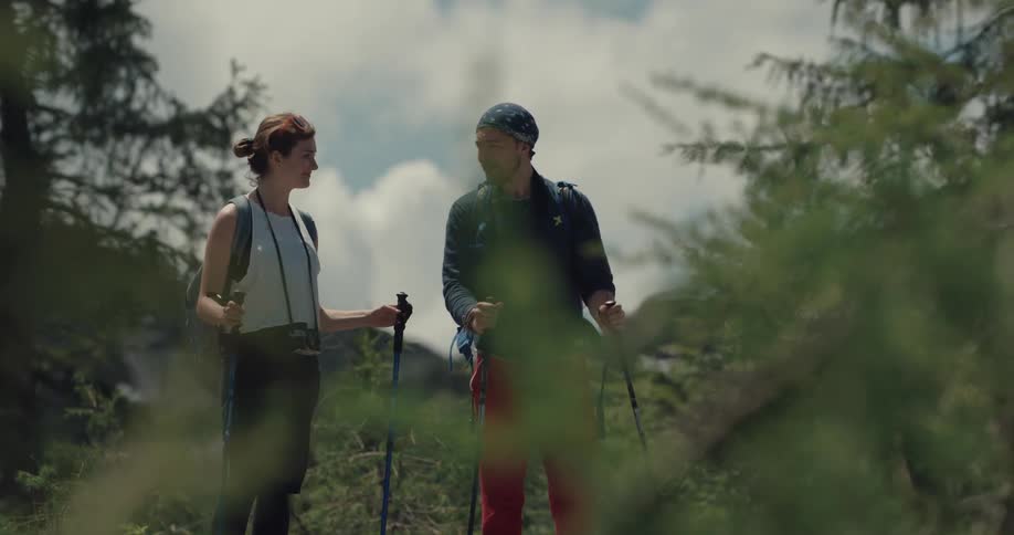 A man and woman take a brief break to talk while hiking