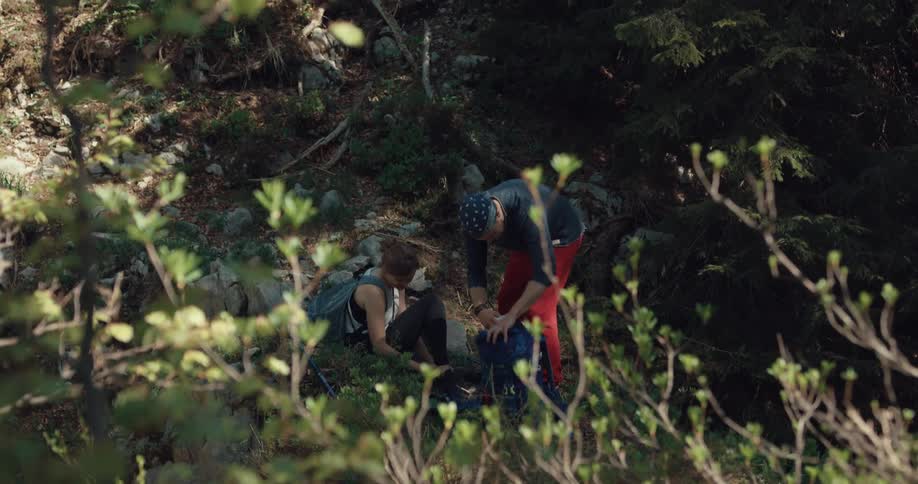 Man helping an injured woman sitting on a trail in the forest