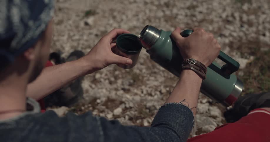 A man pours a drink for a woman from his thermos