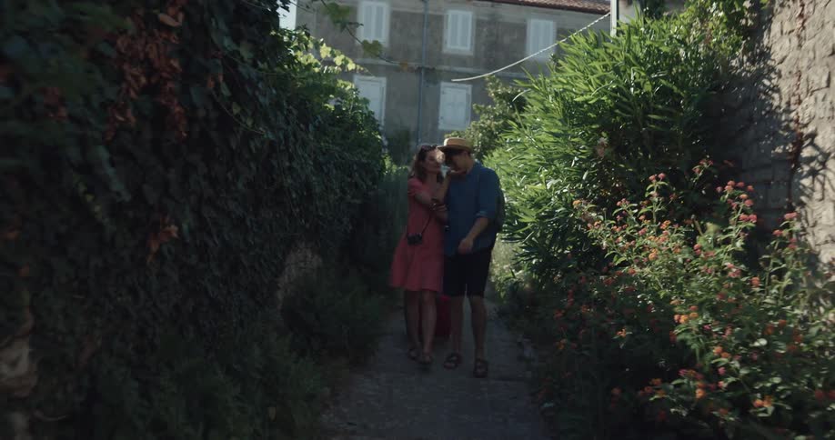 A man and woman walking down a pathway with a suitcase