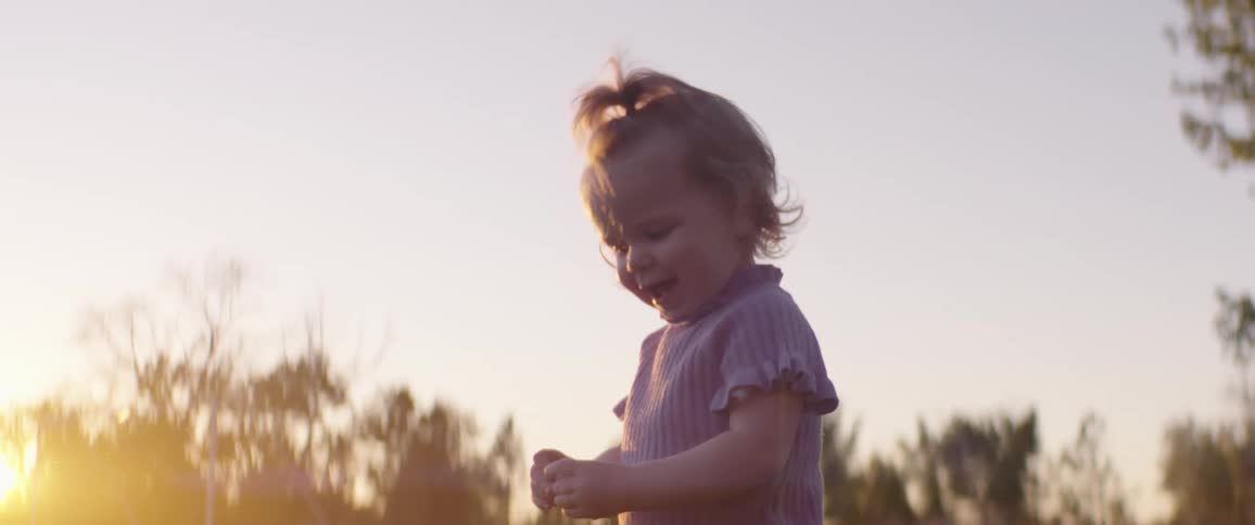 Baby girl jumping up and down at the park