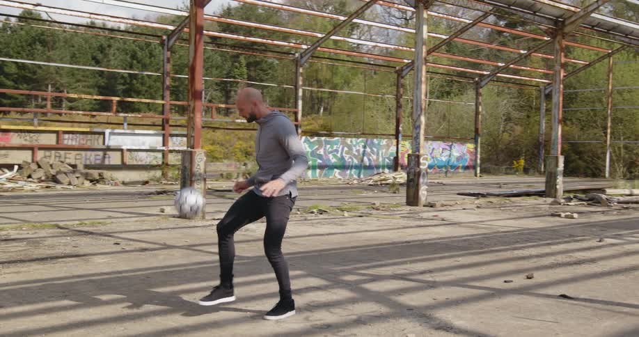 A man playing with a soccer ball with trees the sky and clouds in the background