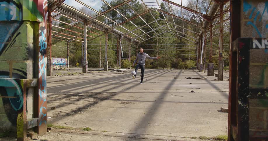 A man kicking a soccer ball around outdoors