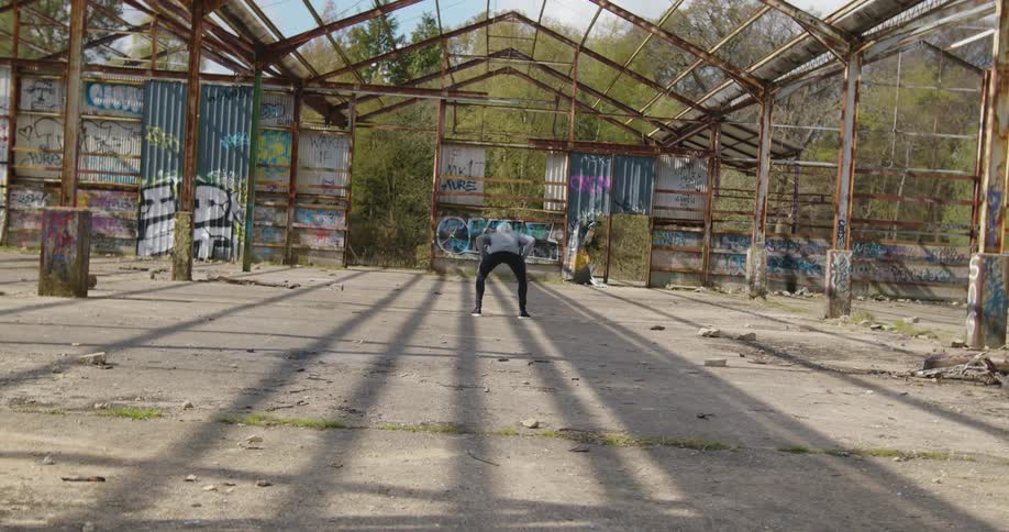 A man is balancing a soccer ball on his head inside the frame of a building