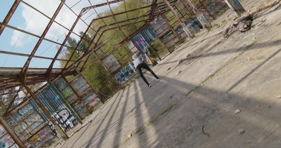 A man is moving a soccerball into the air inside the frame of a building