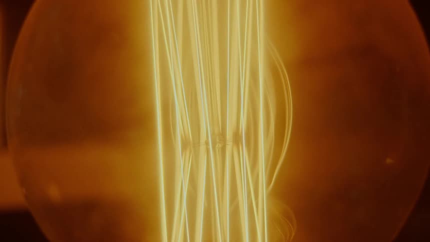 A light bulb glows orange and yellow against black