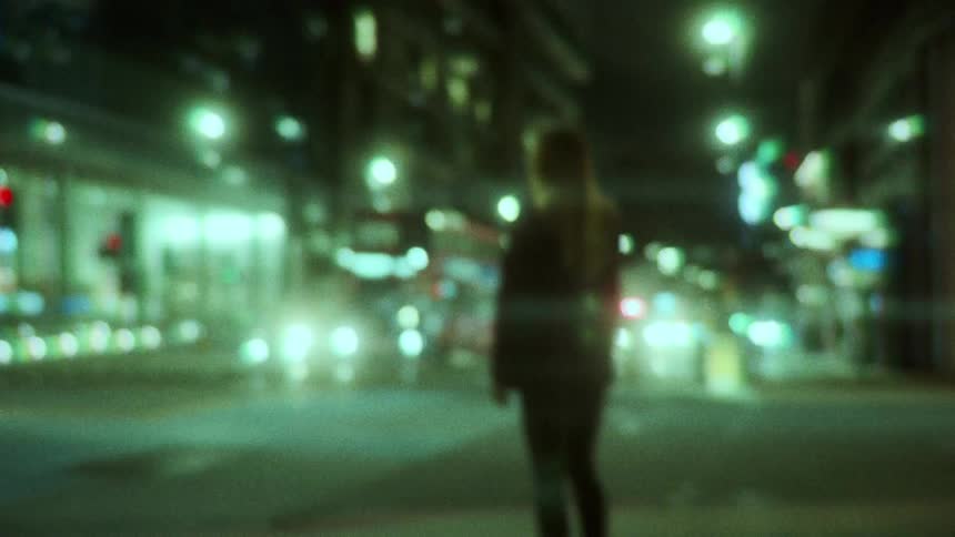 A woman is walking through a downtown city at night