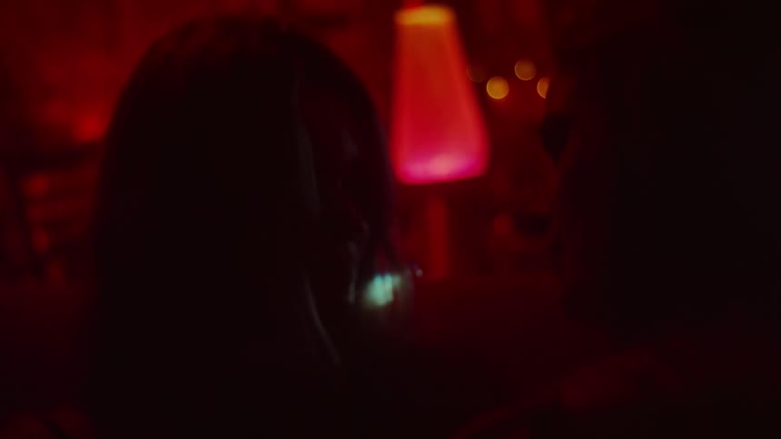 Two women look lovingly into each others eyes in a darkened room