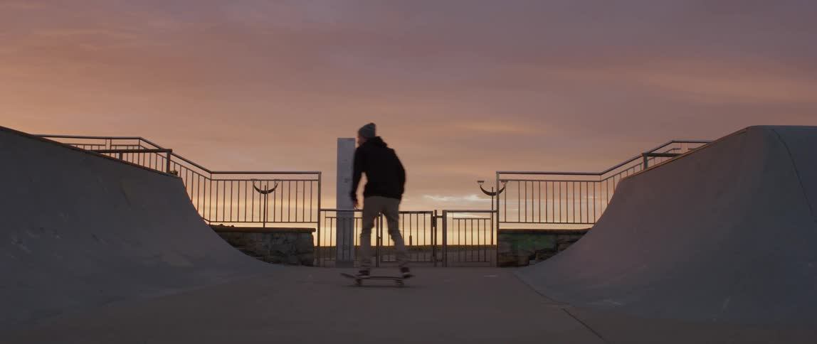 A young male rides a skateboard on a skate track at a park