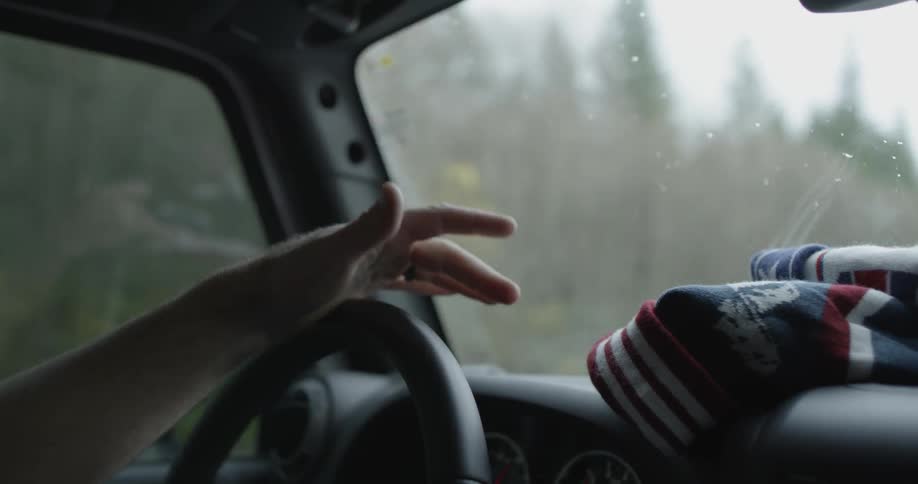 A person tapping their hand on a steering wheel as they drive