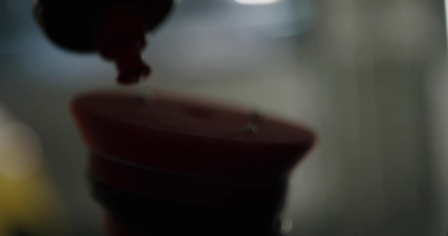 A person squeezes dots of wax from a bottle onto a car buffer