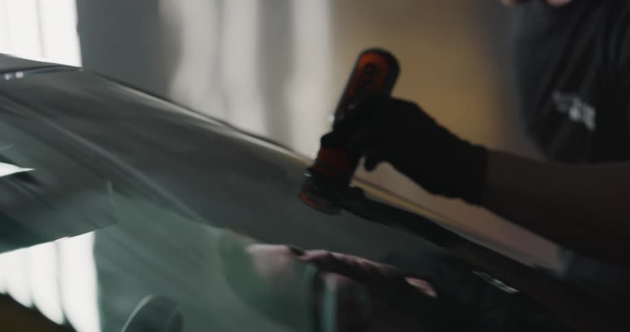 Man applies a substance from a bottle onto a windshield of a vehicle