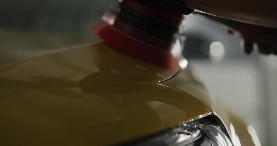 A person in a room using a tool to wax a vehicle