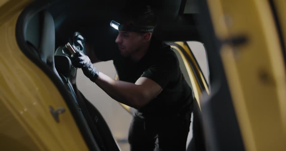 A male car detailer scrubbing the back seat of a car