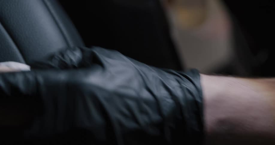 Person wearing black gloves adds soap from pump onto brush before cleaning leather