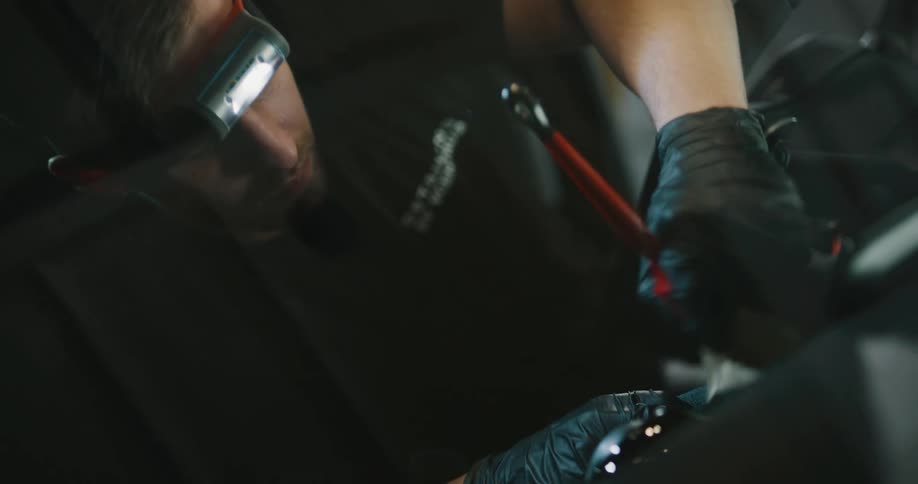 A male car detailer cleaning the dashboard of a car while wearing a headlamp