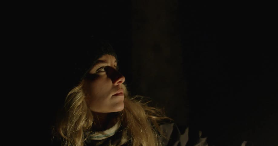 A blonde woman looking around in a dark area