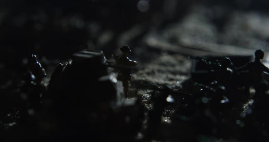 Light plays over miniature soldiers and tanks set on terrain