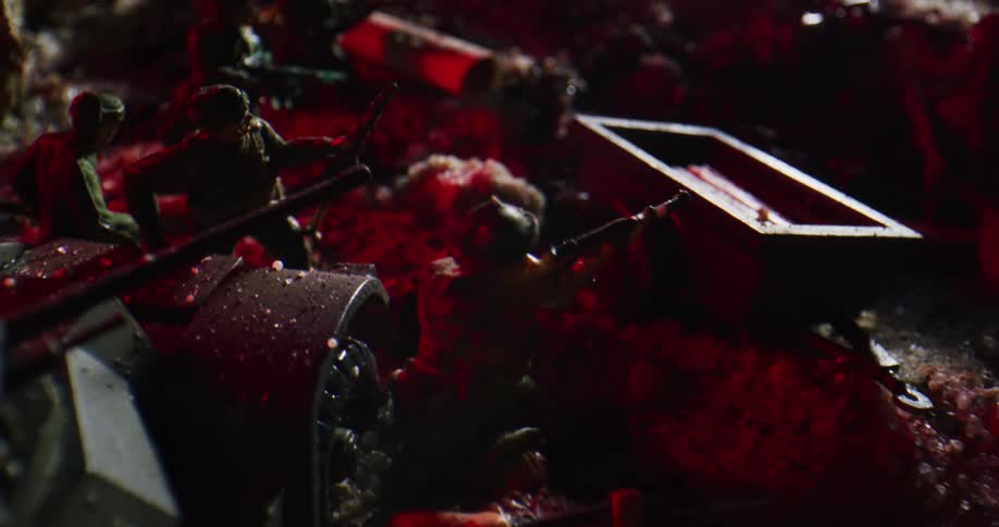 Toy army men and a toy tank with flashing lights in the background