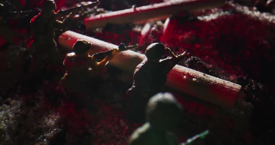 Toy soldiers with rifles drawn sit behind pieces of wood resembling fallen tree trunks