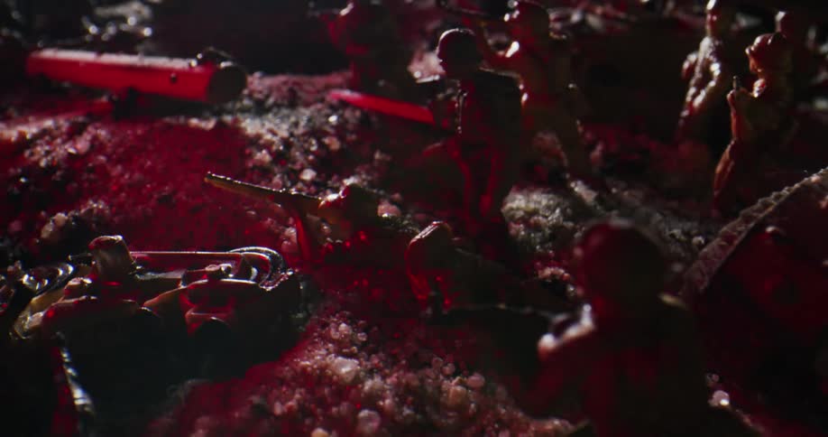 A number of plastic figurines of soldiers are positioned on a sandy surface