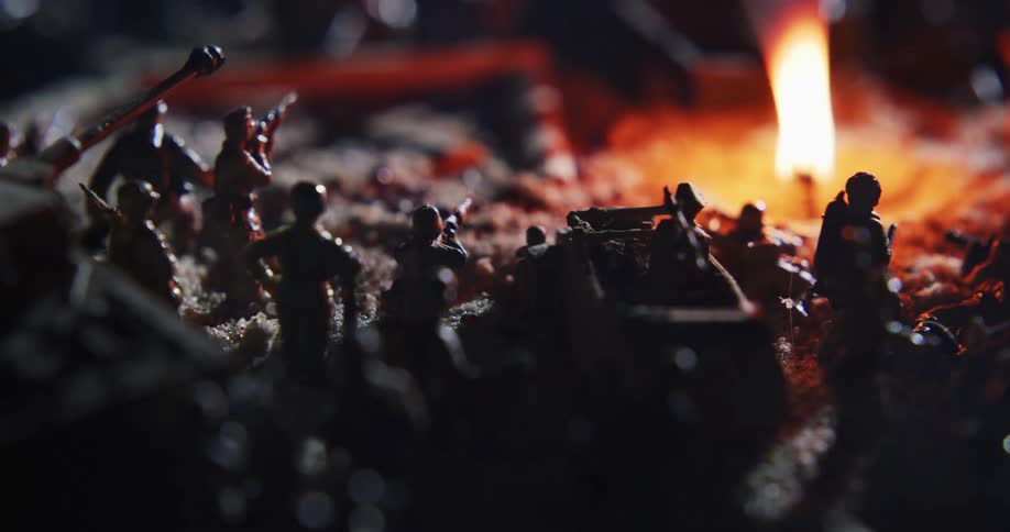 Toy soldiers are arranged in dirt around a trench with a burning candle