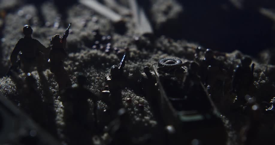 Toy soldiers are placed in dirt around a tank outside