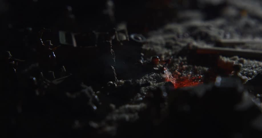 Flame burns in small pit in middle of diorama of soldier and vehicle miniatures