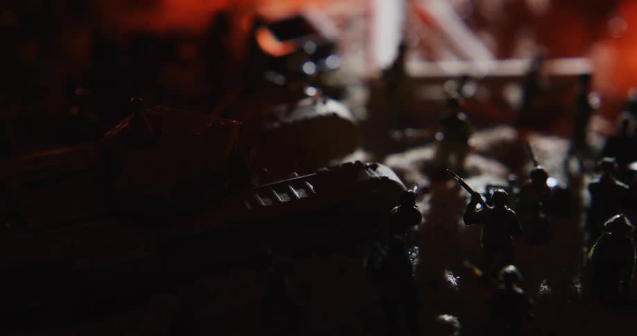 Lights move across miniature soldiers and vehicles sitting in shadow