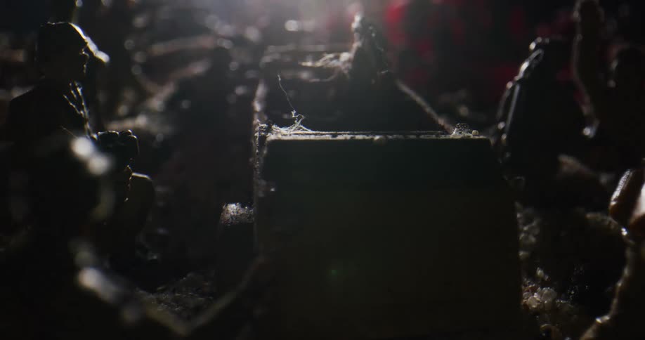 Toy soldiers are arranged around a toy tank in dirt