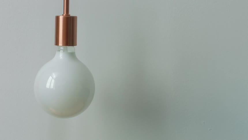 A room with a lightbulb and light fixture with a wall in the background