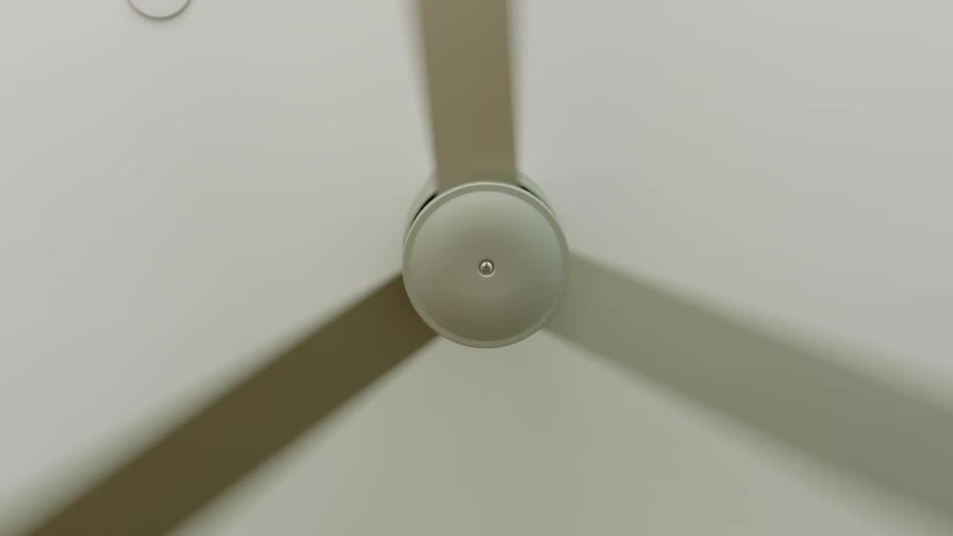 A basic ceiling fan with three blades spins slowly overhead