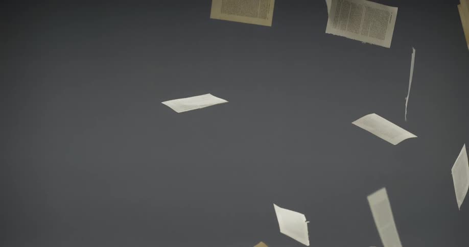 Pages of a book falling in the air in front of a wall