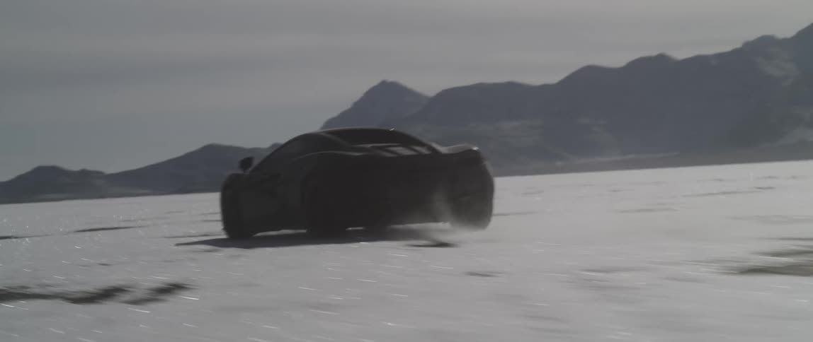 A view of a car driving on a snowy dry lake bed