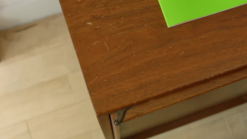 A person in a room taking plane tickets from a table with a wall in the background