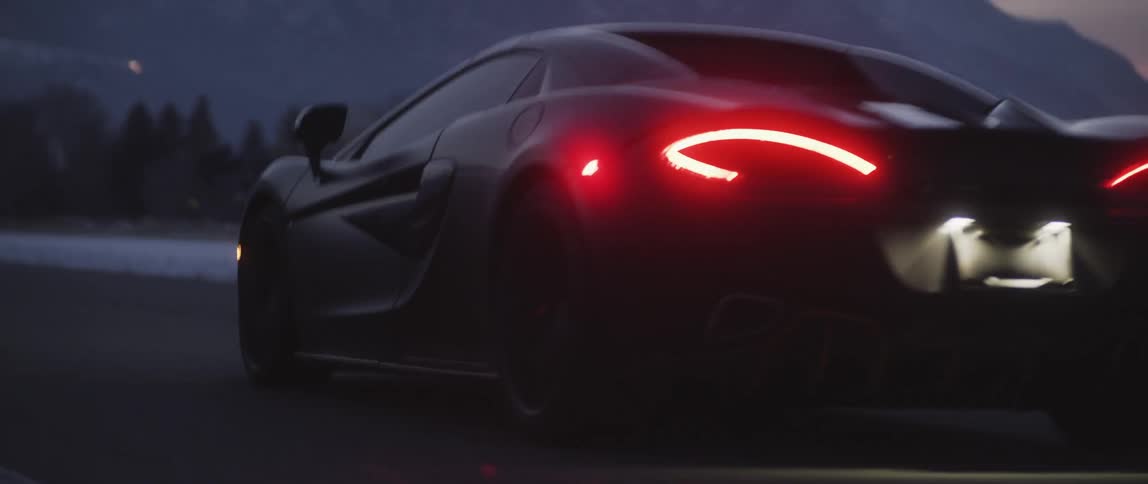 A sports car travels down a country road in the evening