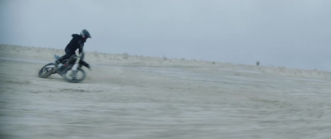 A man is spinning on his dirt bike in the sand