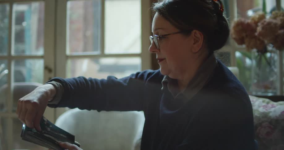 Woman looks at photos that she is holding in her hand and rearranges one that is upside down