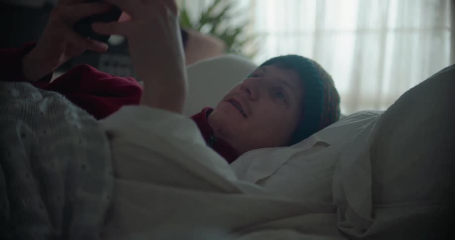 A man typing on a smartphone in a bed