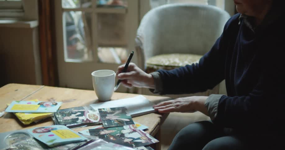 A woman smiles as she drinks coffee and organizes photos