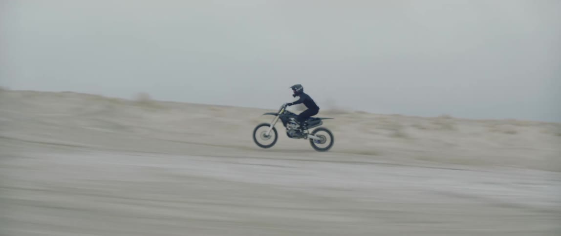 A motorbike rider does a wheelie while speeding through the desert