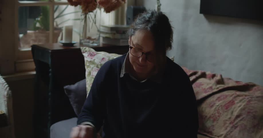 Woman sitting in a couch takes notes while looking at photo albums at home