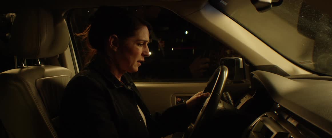 A woman sitting in her car closes the door and puts her head down and looks worried