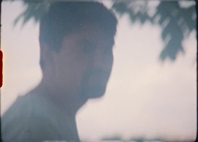 A man laughs before walking off through trees